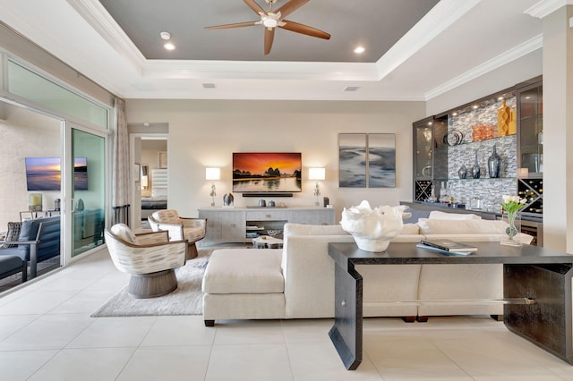 tiled living room with a tray ceiling, crown molding, and ceiling fan