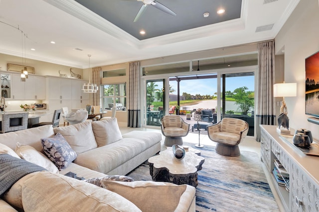 living room featuring a tray ceiling, ceiling fan, and crown molding