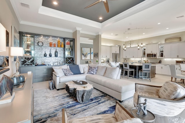 living room featuring ceiling fan, a raised ceiling, and crown molding