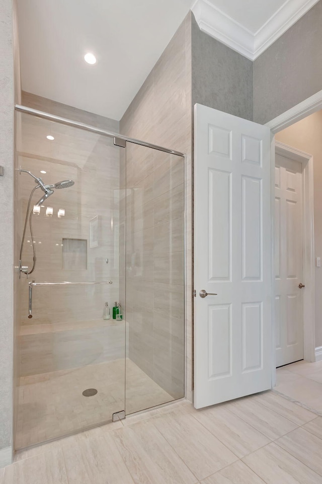 bathroom with a shower with shower door and ornamental molding