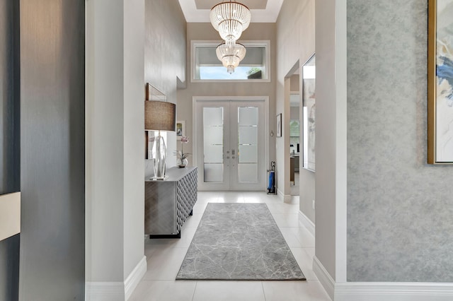 entryway with light tile patterned floors, french doors, a high ceiling, and an inviting chandelier