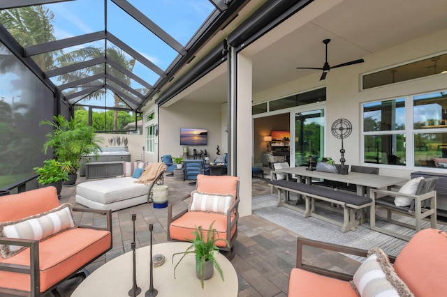 view of patio featuring glass enclosure, ceiling fan, and outdoor lounge area