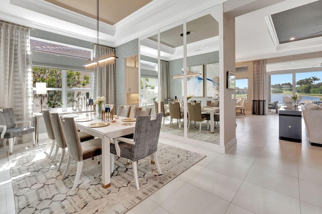 dining room with ceiling fan with notable chandelier, a water view, light tile patterned floors, ornamental molding, and a tray ceiling