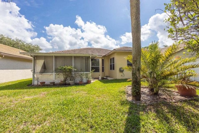 back of house with a sunroom and a lawn