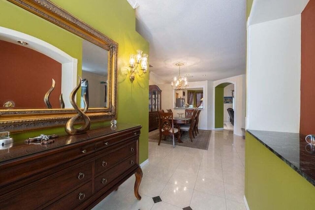 hallway with light tile patterned floors and an inviting chandelier