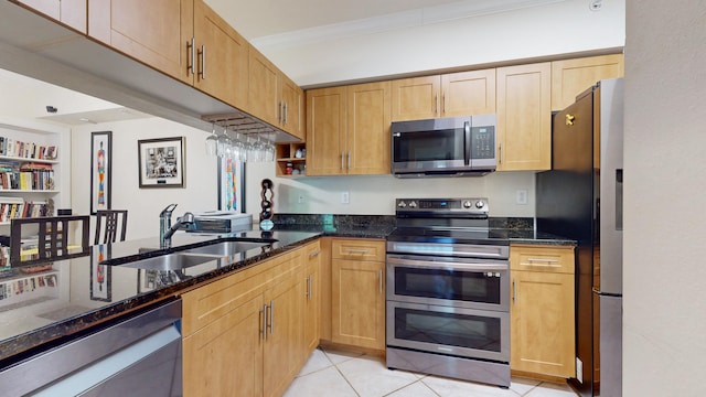 kitchen with sink, dark stone countertops, light tile patterned floors, ornamental molding, and stainless steel appliances