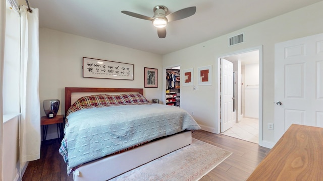 bedroom with wood-type flooring, a walk in closet, a closet, and ceiling fan