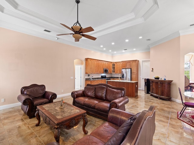 living room featuring a tray ceiling, crown molding, and ceiling fan