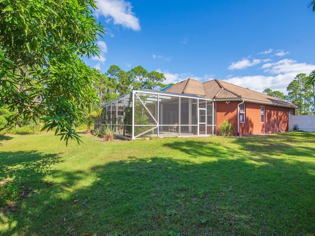 rear view of house featuring a lanai and a lawn