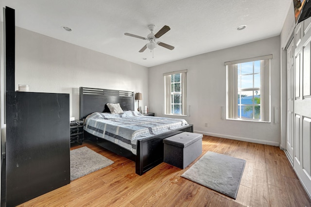 bedroom with ceiling fan, baseboards, and light wood-style floors