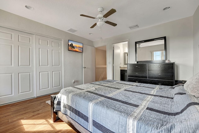 bedroom with a closet, visible vents, a ceiling fan, and wood finished floors