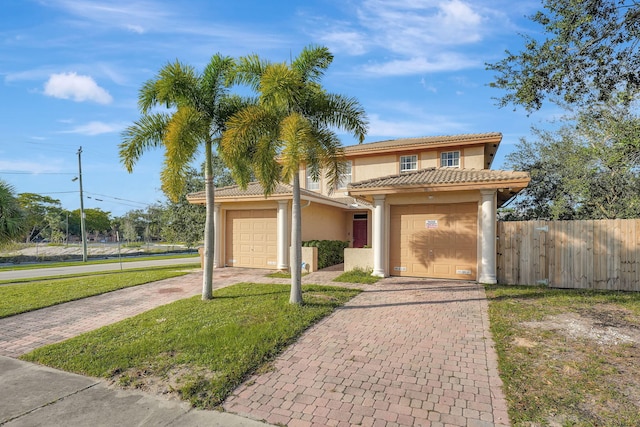 mediterranean / spanish home with stucco siding, an attached garage, decorative driveway, and fence