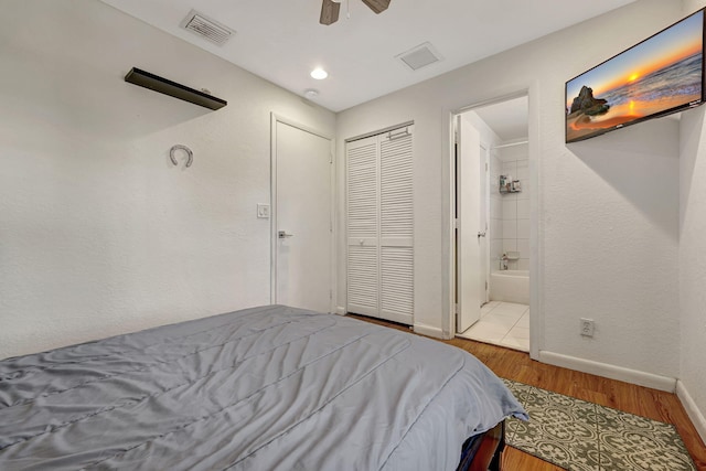 bedroom featuring visible vents, ensuite bath, baseboards, and wood finished floors