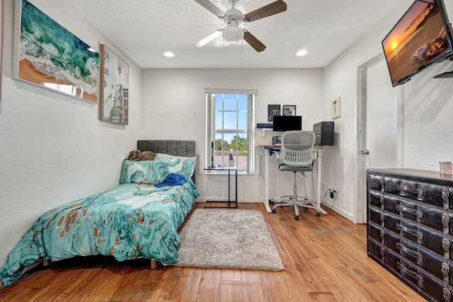 bedroom with a ceiling fan, wood finished floors, baseboards, recessed lighting, and a textured ceiling