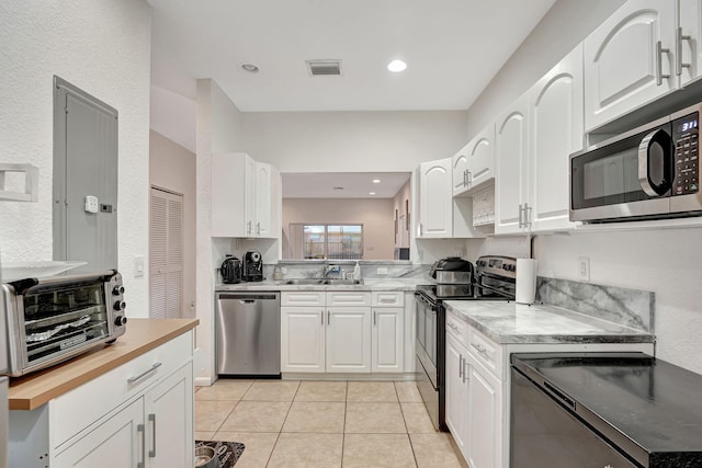 kitchen with visible vents, butcher block countertops, a sink, white cabinetry, and stainless steel appliances