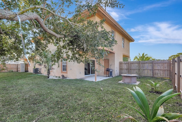 back of house featuring stucco siding, central AC unit, a fenced backyard, a yard, and a patio area