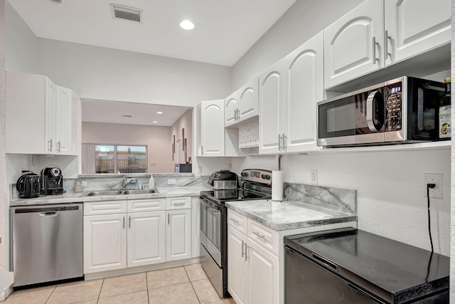 kitchen with visible vents, light tile patterned floors, stainless steel appliances, white cabinetry, and a sink