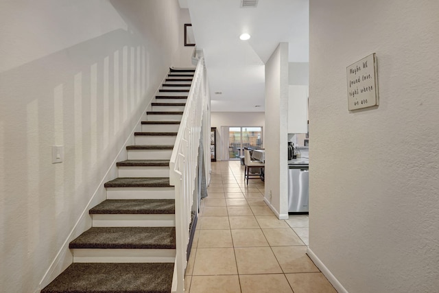 stairs with tile patterned floors, visible vents, baseboards, and a textured wall