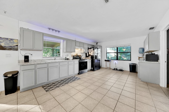 kitchen with sink, light stone counters, a healthy amount of sunlight, and black appliances