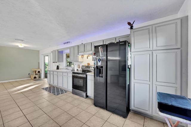 kitchen with gray cabinets, black refrigerator with ice dispenser, stainless steel range with electric cooktop, and light tile patterned floors