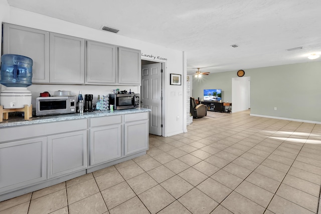 kitchen with gray cabinetry, ceiling fan, and light tile patterned floors