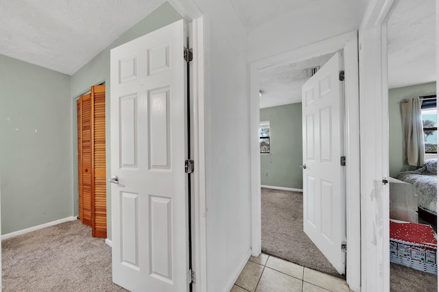 hallway featuring light carpet and a textured ceiling