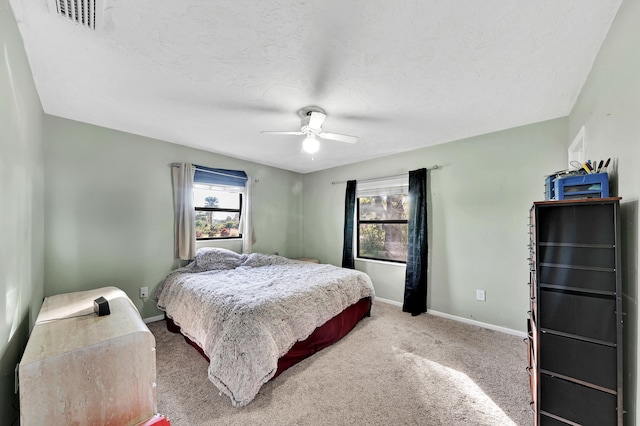 bedroom featuring ceiling fan, carpet floors, and a textured ceiling