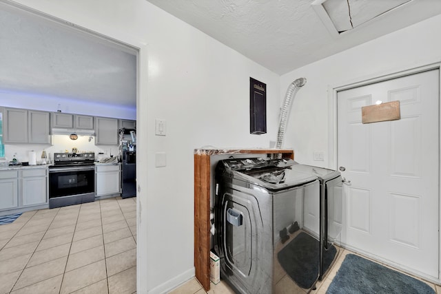 kitchen with gray cabinetry, stainless steel electric range oven, a textured ceiling, light tile patterned floors, and washer and dryer