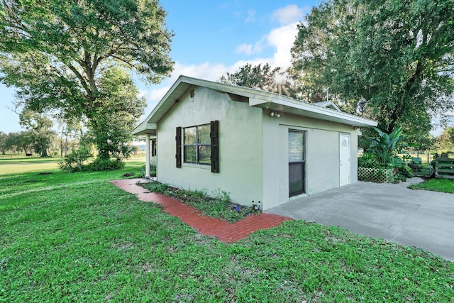 view of side of home with a lawn and a patio area