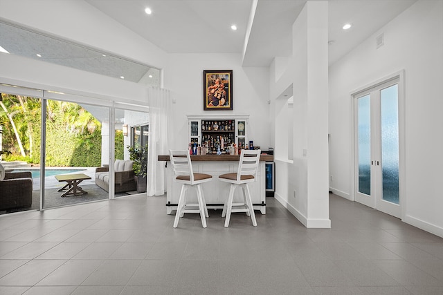 dining area with a high ceiling, bar, and french doors