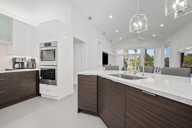 kitchen featuring stainless steel double oven, vaulted ceiling, sink, pendant lighting, and white cabinetry