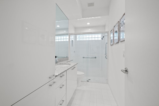 bathroom featuring tile patterned flooring, vanity, toilet, and walk in shower