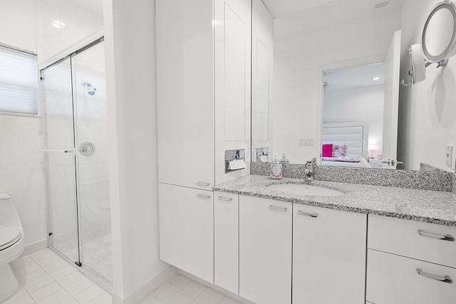 bathroom featuring tile patterned flooring, vanity, toilet, and walk in shower