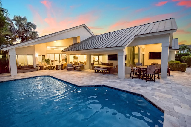 back house at dusk with a patio area and an outdoor living space