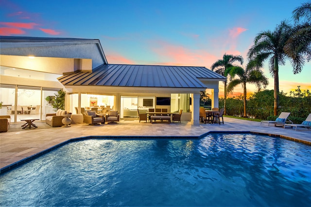 pool at dusk featuring an outdoor living space and a patio