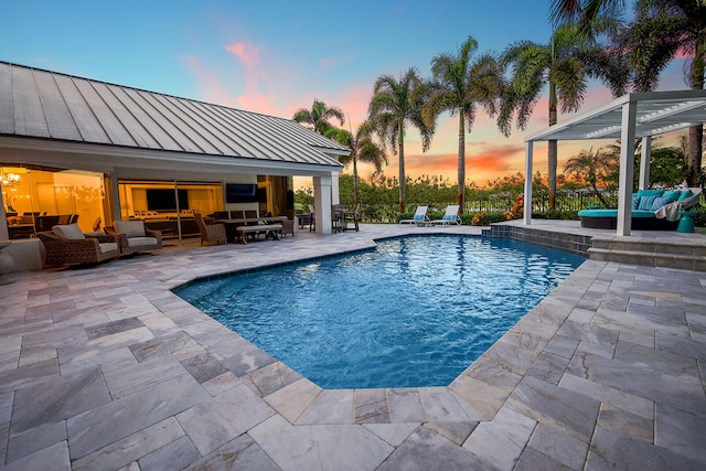 pool at dusk with outdoor lounge area and a patio area