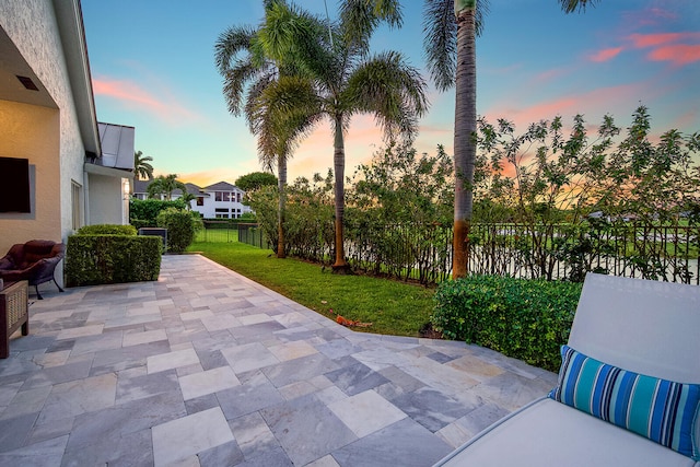 patio terrace at dusk featuring a lawn