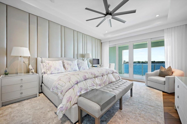 bedroom featuring a tray ceiling, access to exterior, ceiling fan, and light hardwood / wood-style floors