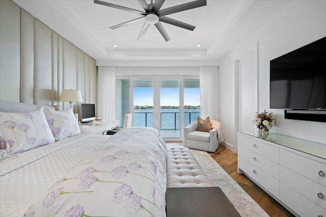 bedroom with a raised ceiling, access to exterior, ceiling fan, and dark hardwood / wood-style floors