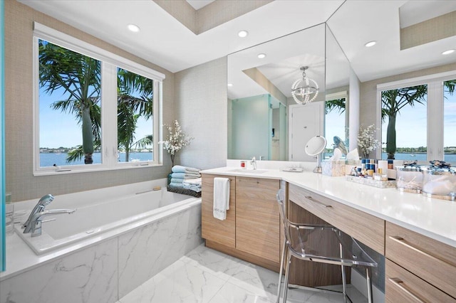 bathroom featuring vanity, a water view, tiled tub, and a notable chandelier