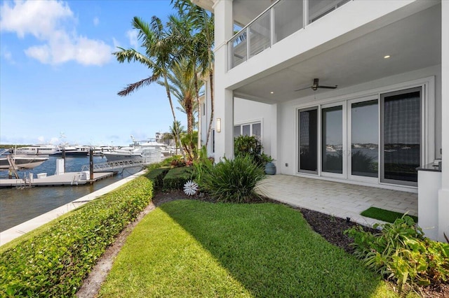 view of yard featuring ceiling fan, a water view, and a dock