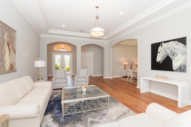 living room featuring a tray ceiling, french doors, ornamental molding, and hardwood / wood-style flooring