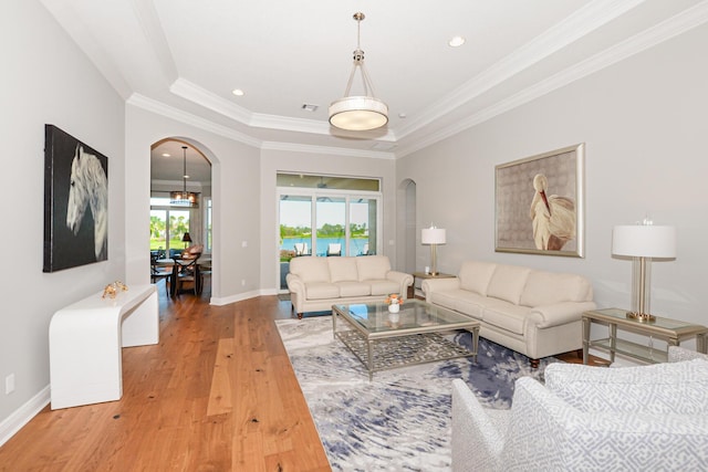 living room with a raised ceiling, ornamental molding, and hardwood / wood-style flooring