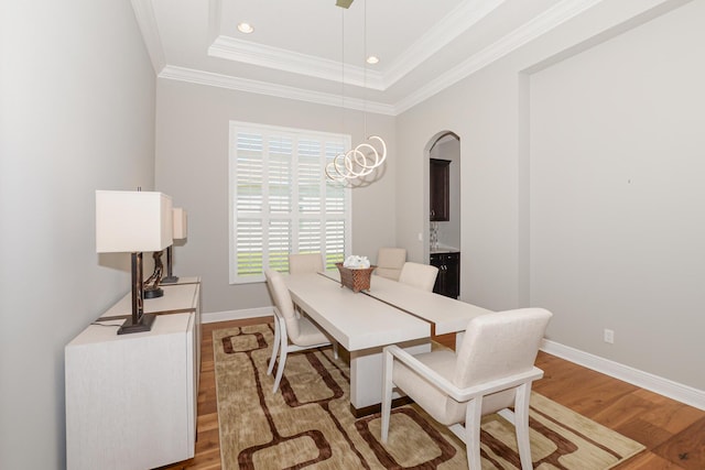 dining area with hardwood / wood-style flooring, a raised ceiling, and ornamental molding