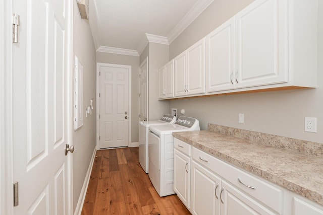 clothes washing area with washer and dryer, cabinets, light wood-type flooring, and ornamental molding