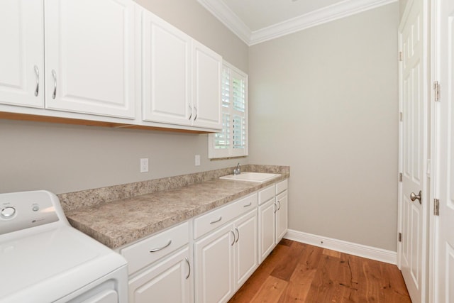 laundry area with cabinets, light wood-type flooring, ornamental molding, sink, and washer / dryer