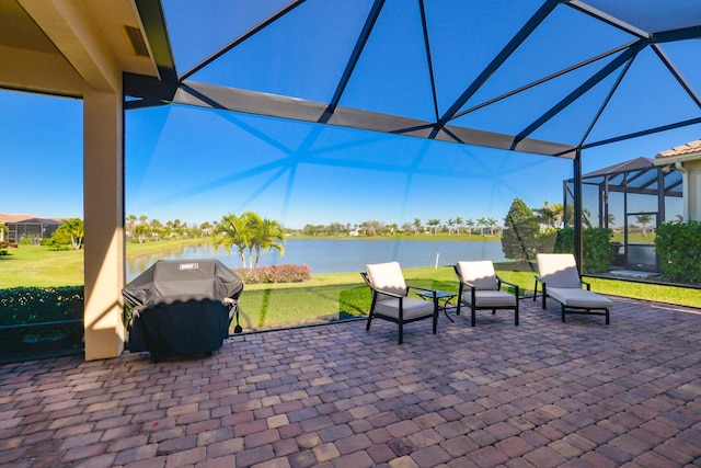 view of patio / terrace featuring a water view, glass enclosure, and a grill