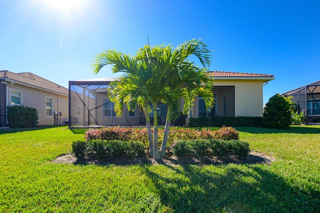 exterior space with glass enclosure and a front yard