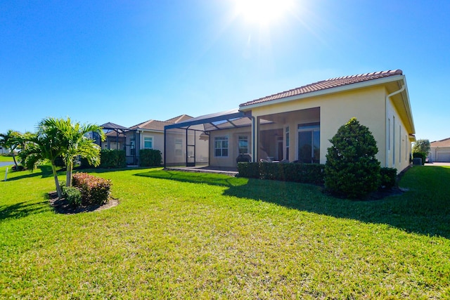 rear view of property with a lawn and a lanai