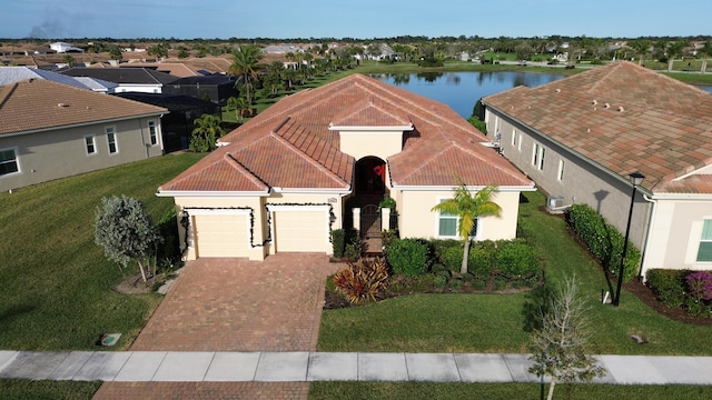 view of front of property featuring a front yard, a wall mounted air conditioner, a water view, and a garage